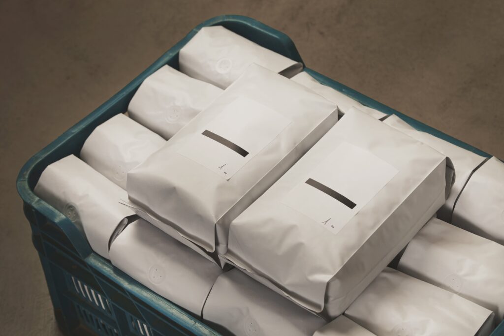 closeup-white-filled-with-coffee-tea-sealed-packages-plastic-box-concrete-floor-warehouse-min